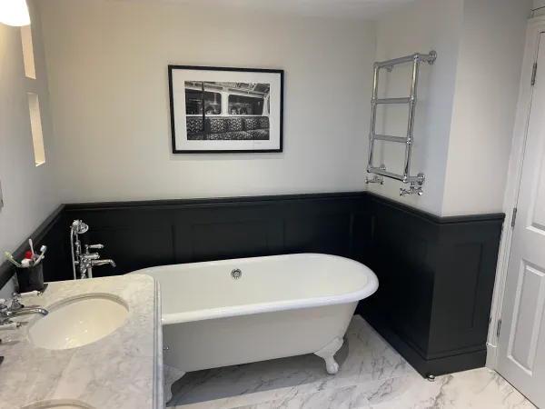 Freestanding bath against dark wall panelling
