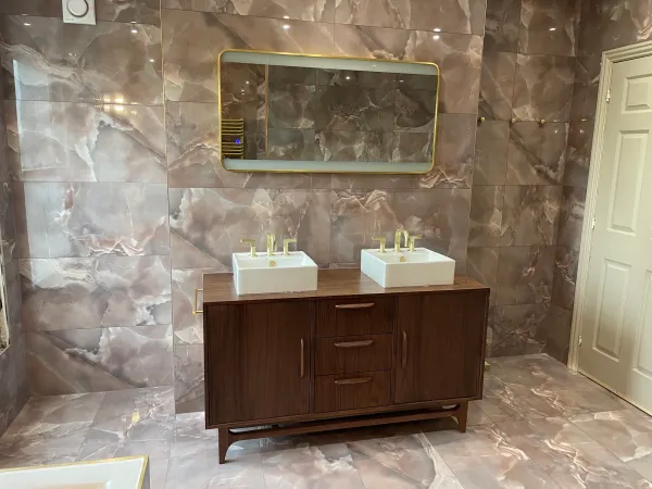 Twin basins and brass taps against expressive marble-effect tiles